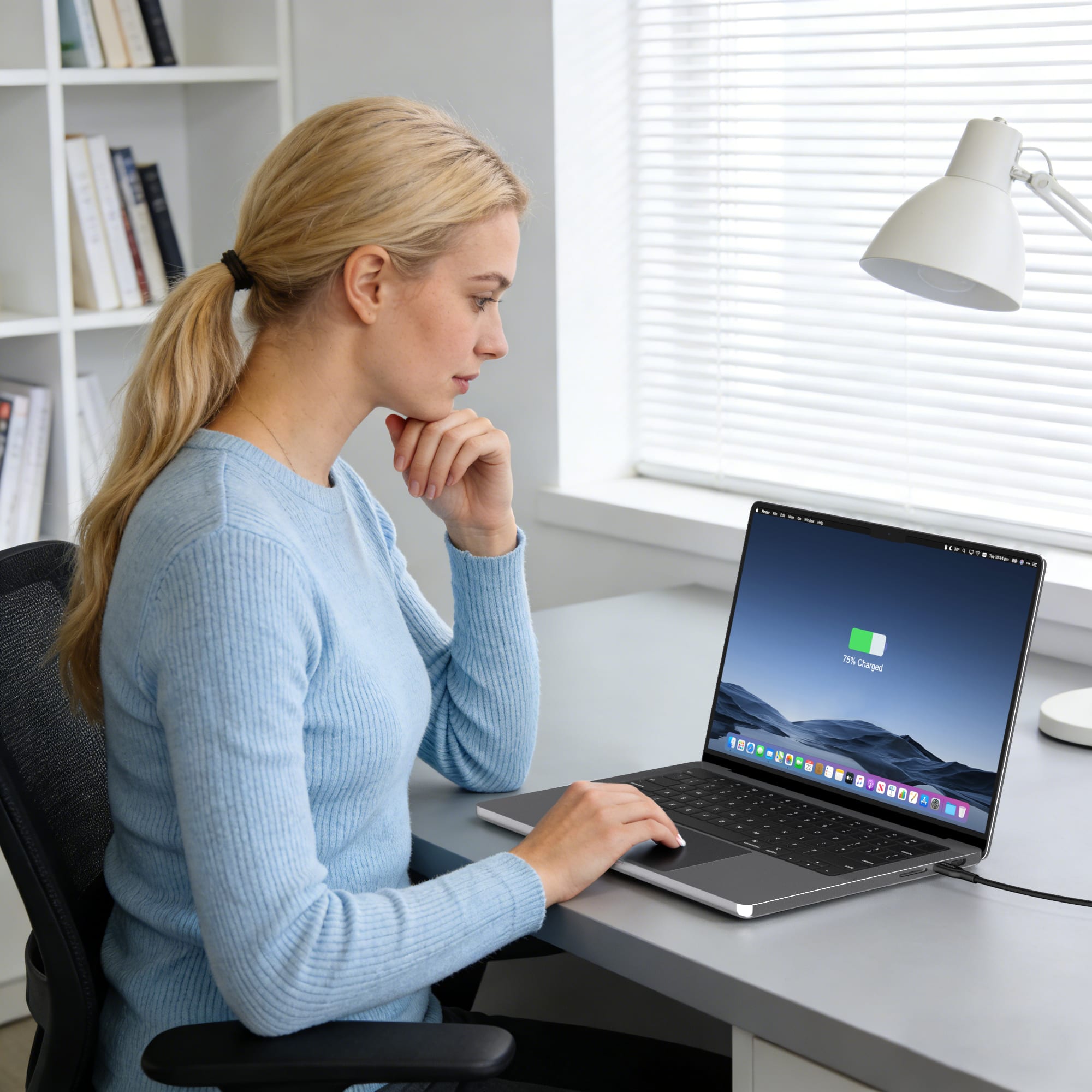 Woman using a laptop at a desk in a home office setting