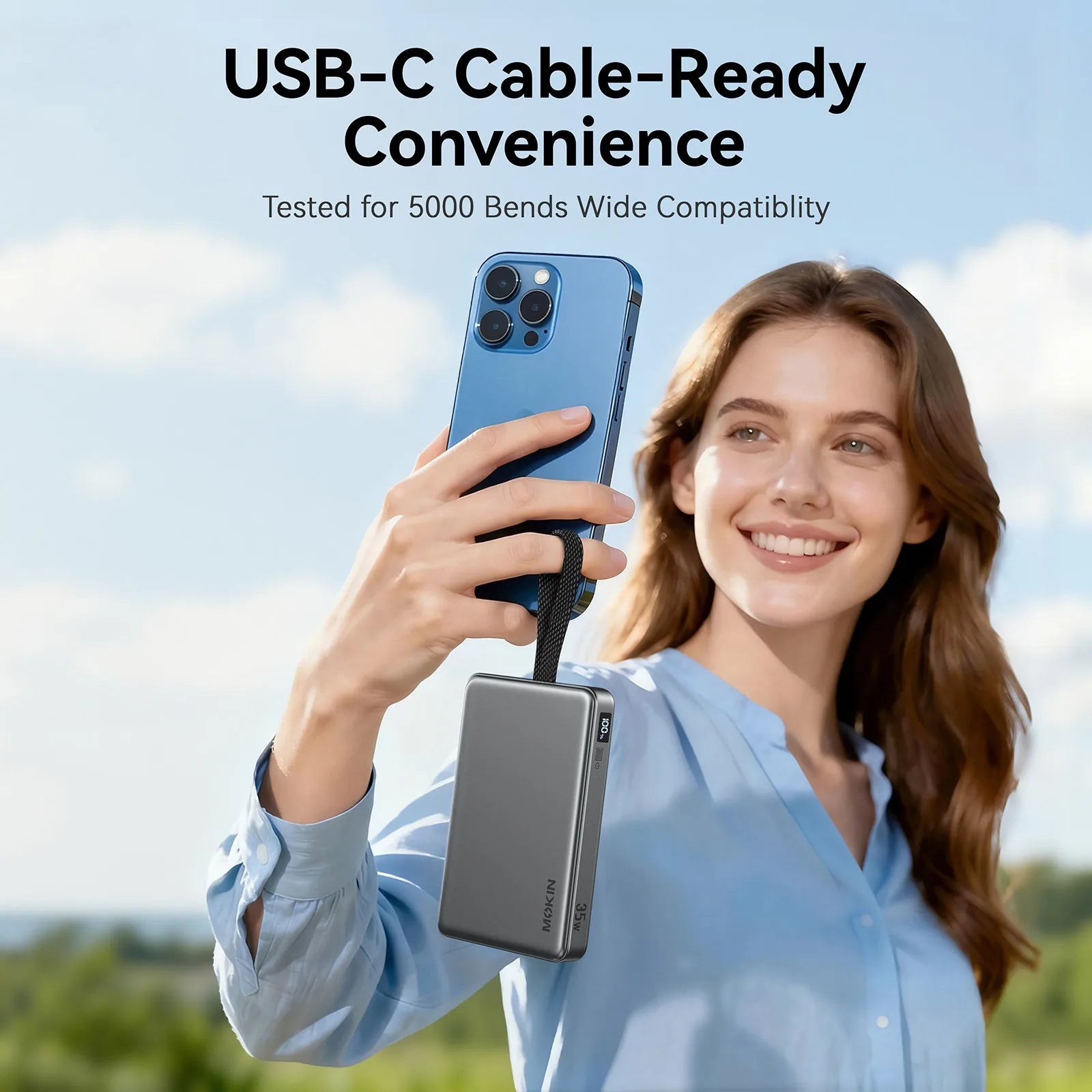 Woman outdoors smiling and holding a blue iPhone connected via the MOKiN built-in USB-C cable to the MOPB0603 power bank dangling below the phone